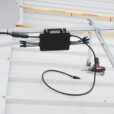 Close-up of solar charge controller installation with cables on a metal roof.