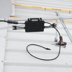 Close-up of solar charge controller installation with cables on a metal roof.