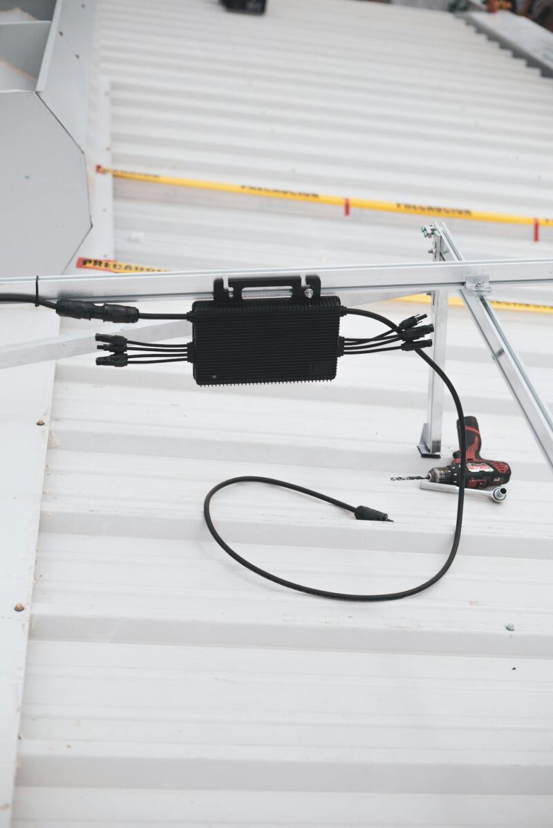 Photo by Los Muertos Crew Close-up of solar charge controller installation with cables on a metal roof.